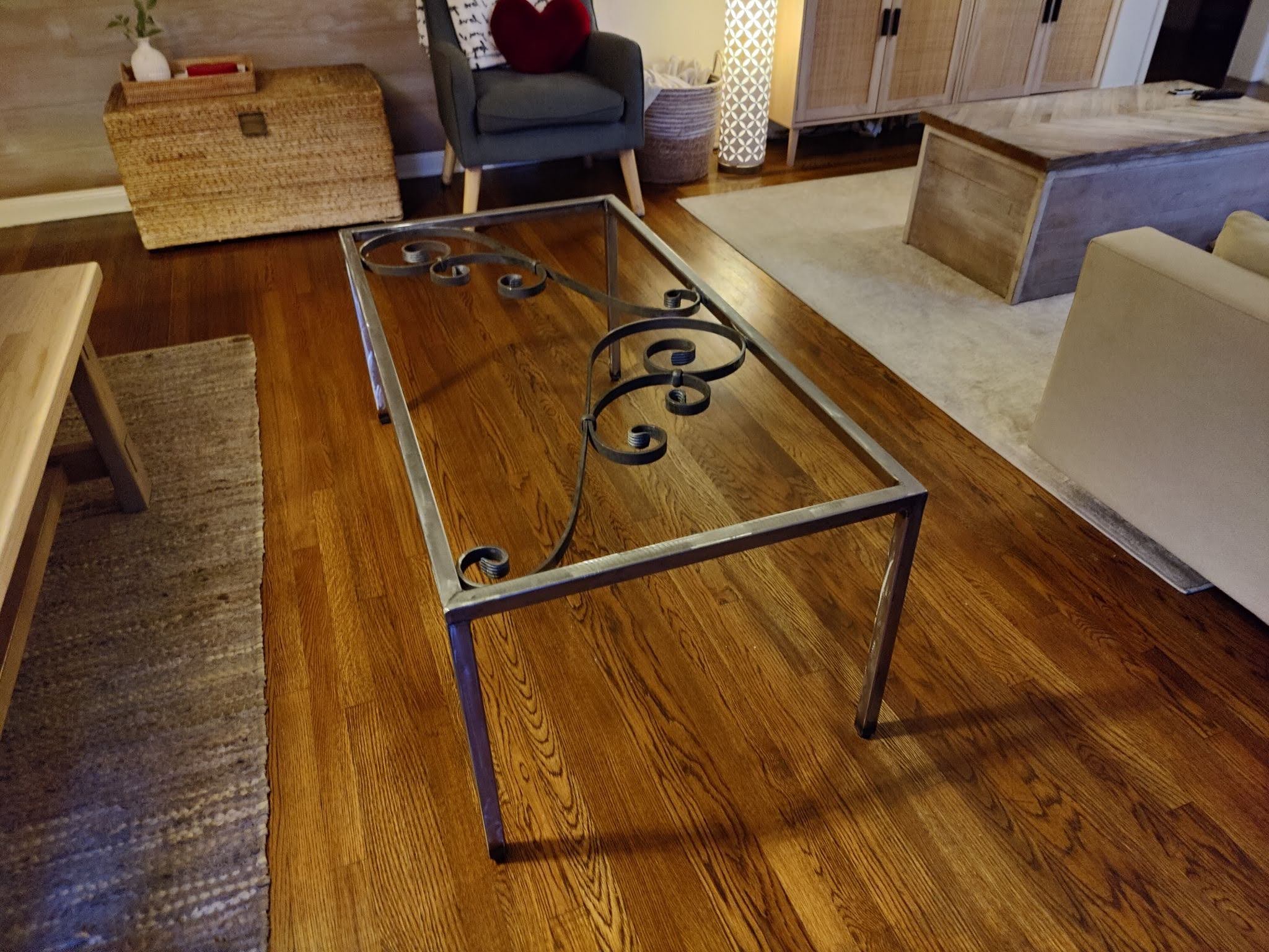 A welded steel-frame coffee table with decorative scrollwork, in a living room.